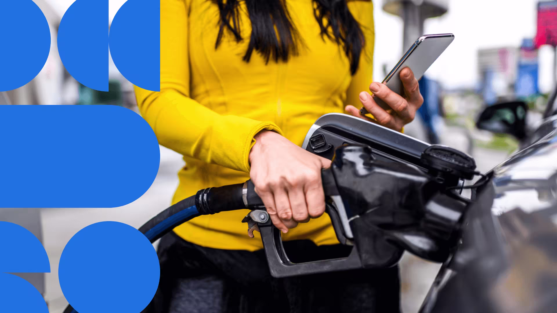 Person in yellow jacket using smartphone while holding a pump at a gas station, with blue circular design elements in background