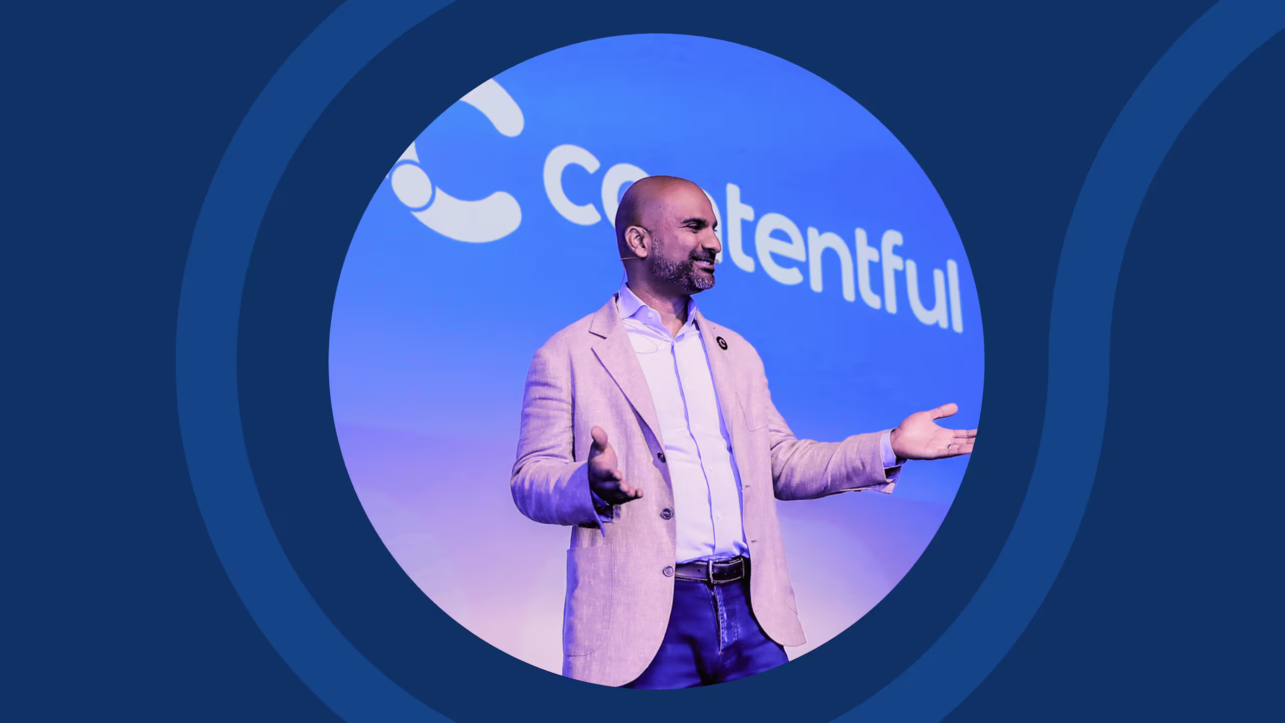 Speaker in light suit gesturing on stage with blue circular backdrop and Contentful logo