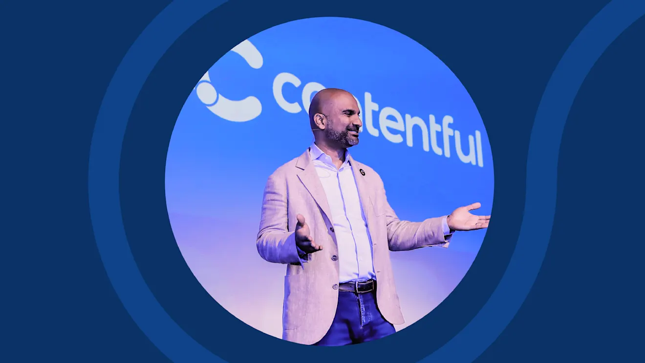 Speaker in light suit gesturing on stage with blue circular backdrop and Contentful logo