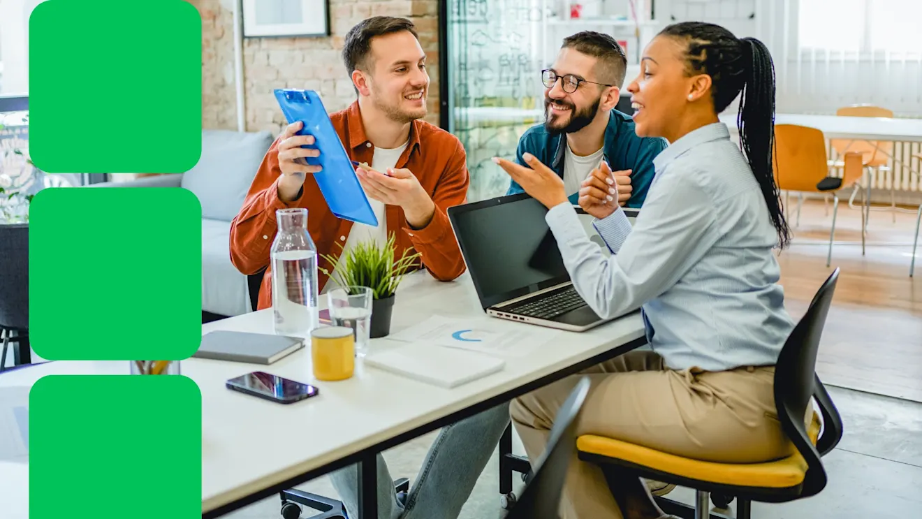 Diverse team members having an animated discussion at modern office desk with laptop and documents, sharing ideas enthusiastically