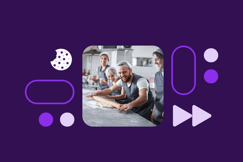 Bakers working together in a commercial kitchen, rolling dough on a flour-dusted counter, surrounded by purple decorative elements