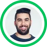 Headshot portrait of a smiling person with dark beard against gray background in circular green frame
