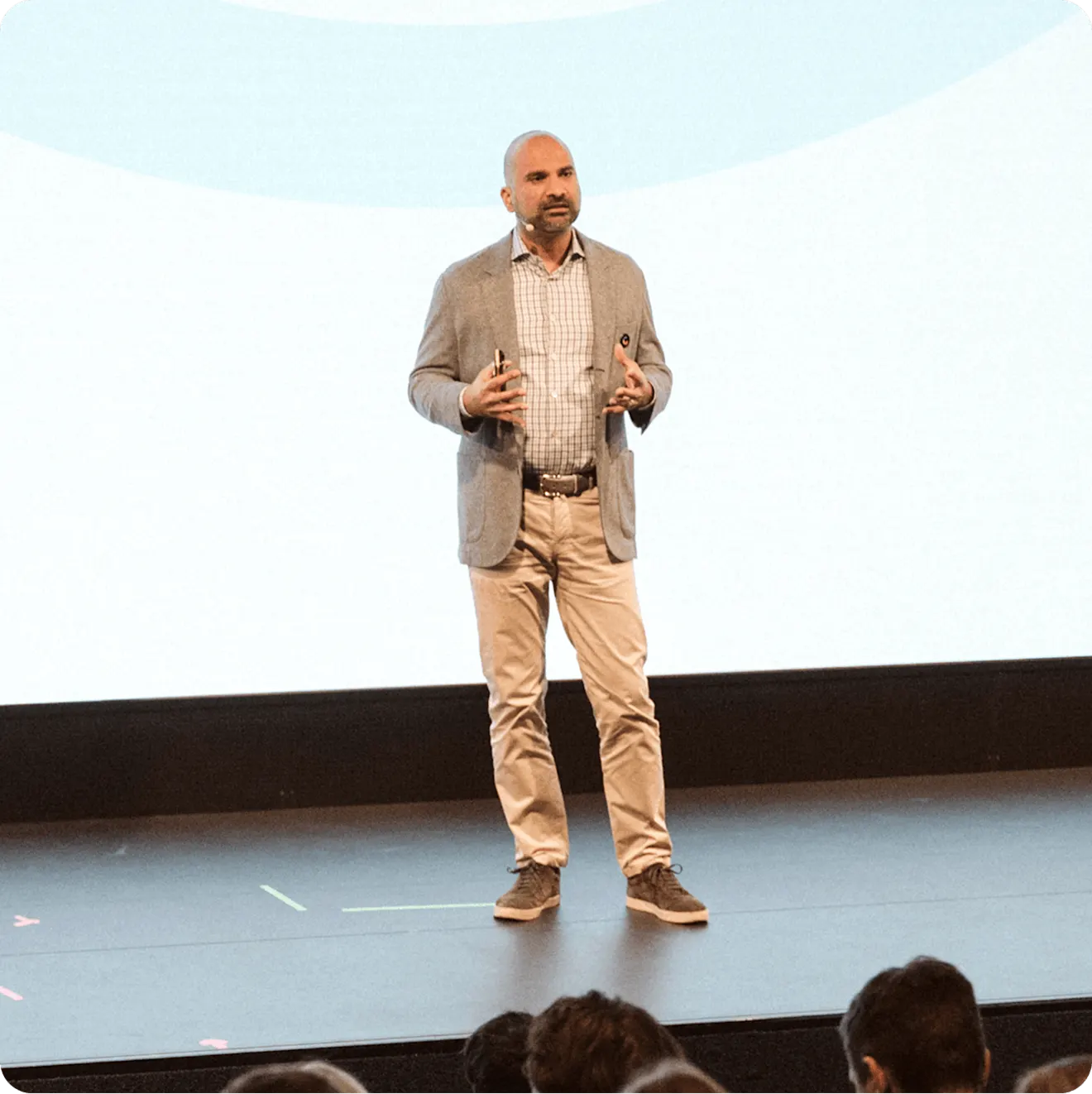 Contentful CEO Karthik Rau in business casual attire gesturing while presenting on stage to an audience in an auditorium