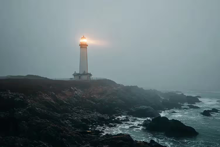 A lighthouse's light piercing through the fog on the coast