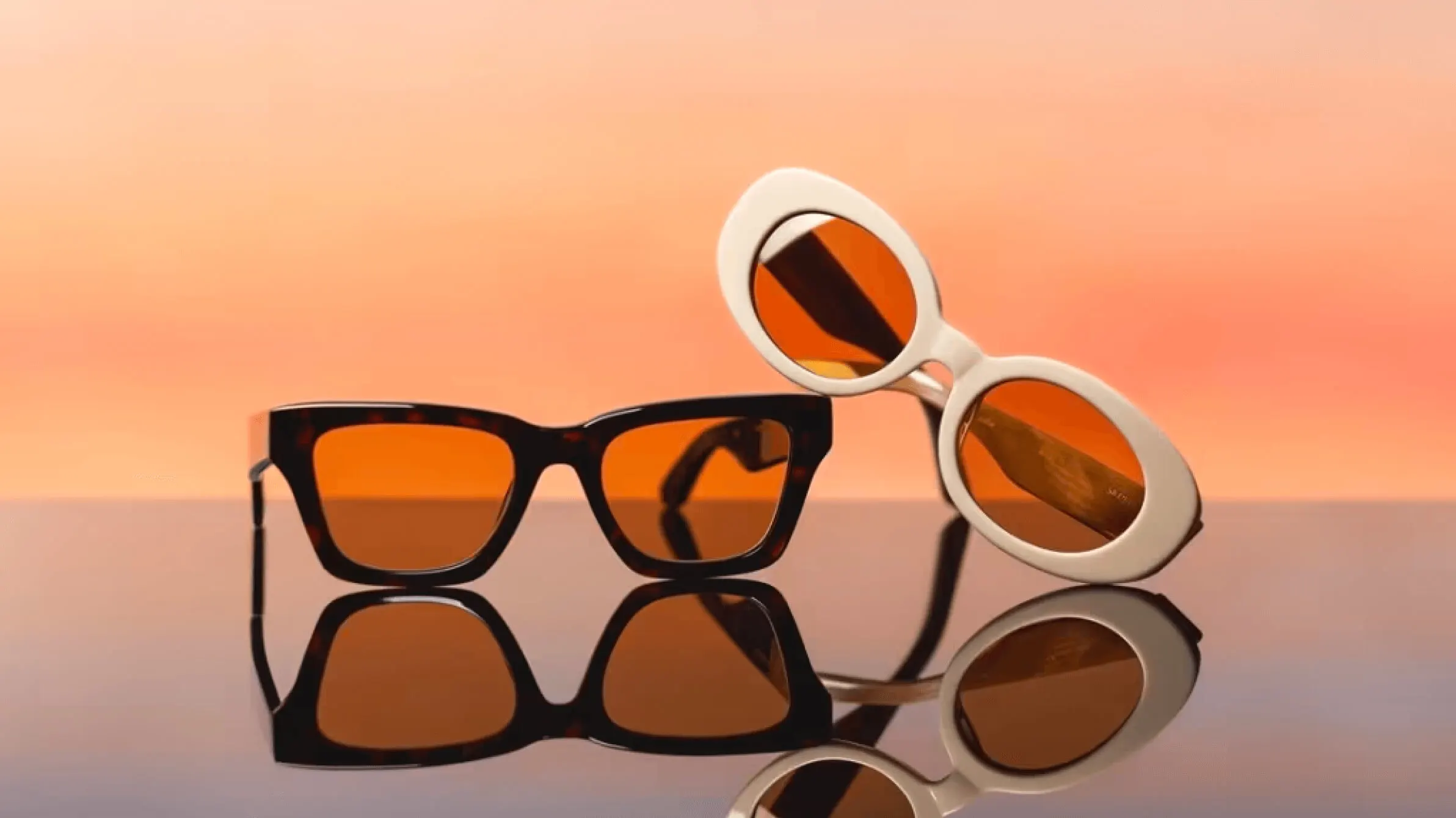 Two pairs of Ace and Tate sunglasses with orange lenses on glossy black surface against warm gradient