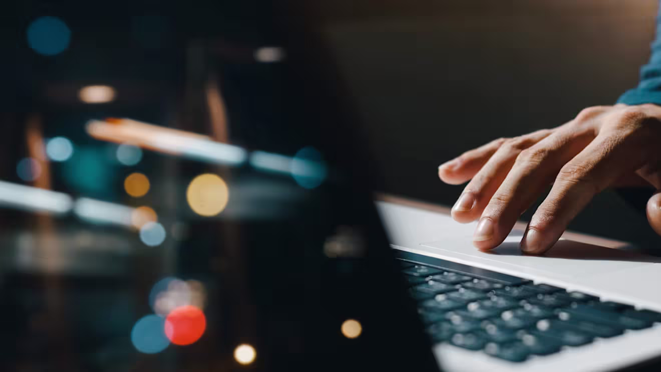 Hand using laptop touchpad against dark background with blurred colorful bokeh lights