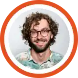 Smiling person with curly brown hair and glasses wearing a light blue shirt against an orange circular background