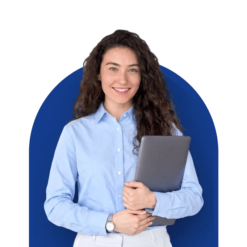Smiling woman with curly hair in a light blue shirt holding a laptop, standing against a dark blue background.